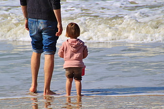 Father and Daughter Standing on Beach Looking at Waves