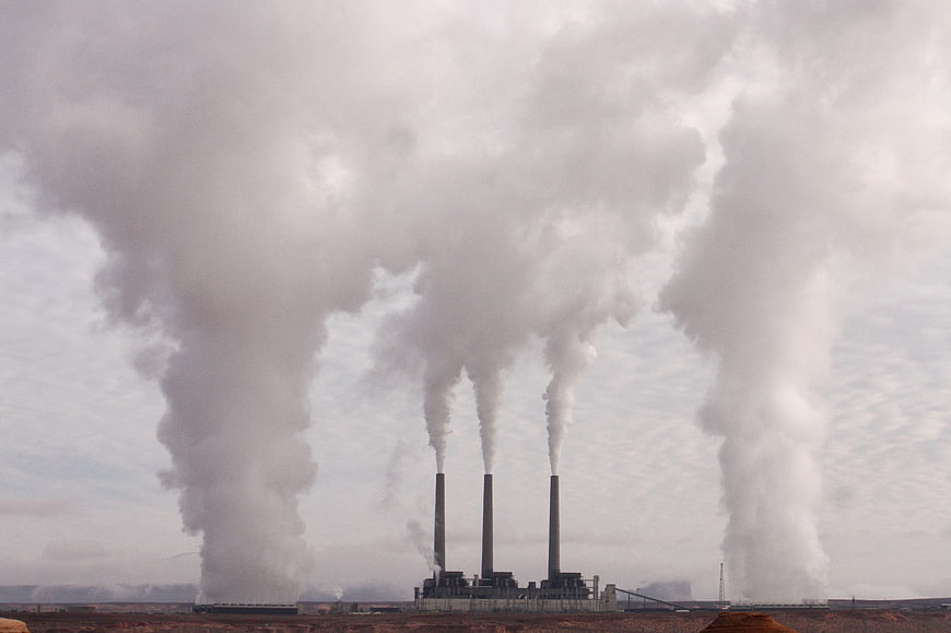 Industrial smokestacks emitting thick white smoke into the sky