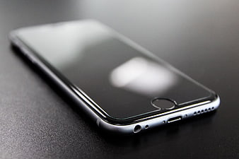 Close-up of a black smartphone on a dark textured surface