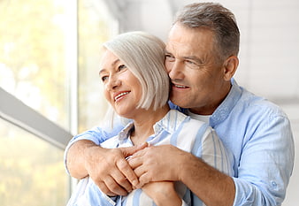 Happy senior couple embracing by window