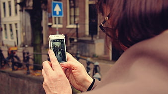 Woman taking photo of canal with smartphone in city