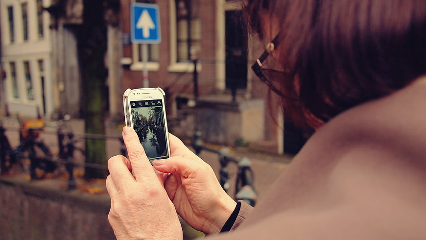 Woman taking photo of canal with smartphone in city