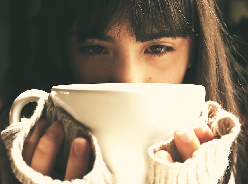 Woman holding warm coffee mug close up