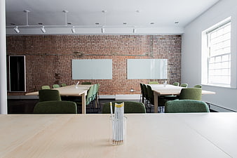 Modern office meeting room with exposed brick wall and green chairs