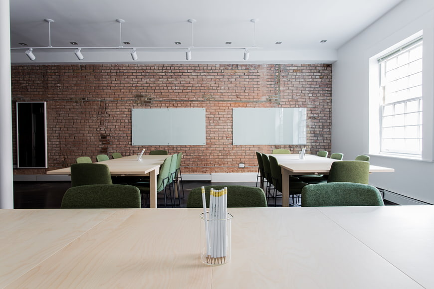 Modern office meeting room with exposed brick wall and green chairs