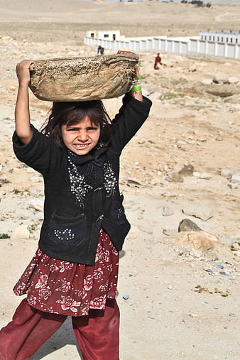 Young Afghan Girl Carrying Heavy Load on Head