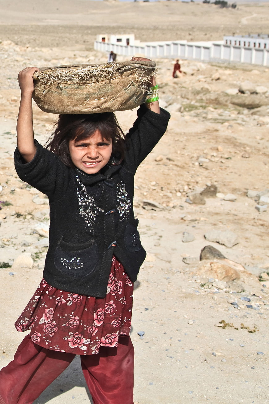 Young Afghan Girl Carrying Heavy Load on Head