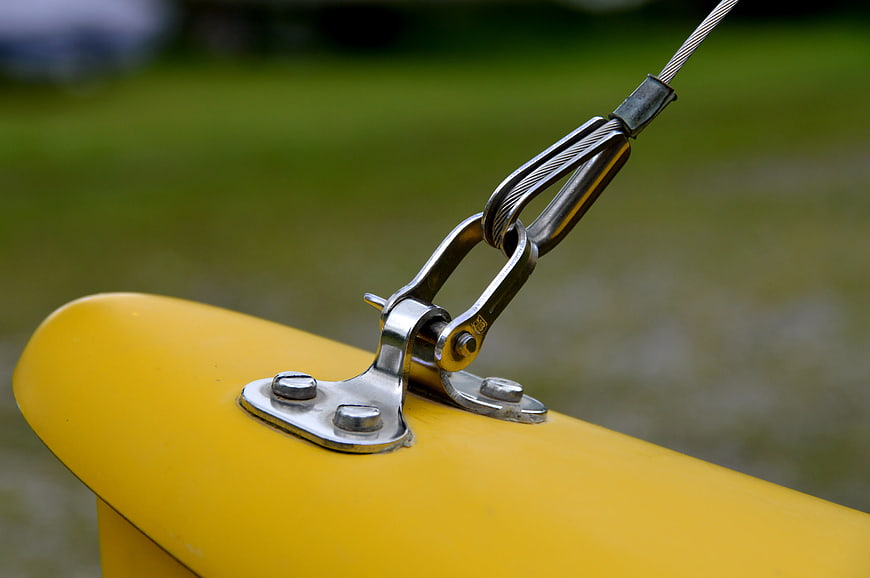 Close-up of metal cable clamp on yellow industrial equipment