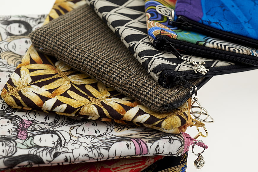 Stack of colorful patterned zipper pouches on white background