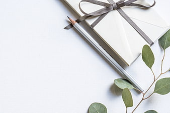 Minimalist white gift box with ribbon, pencil, and eucalyptus leaves