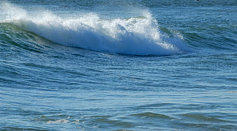 Crashing ocean wave with white foam on blue sea