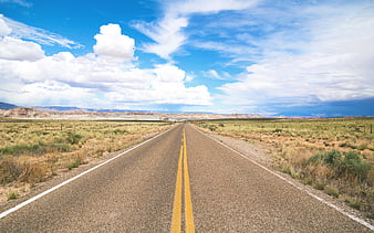 Endless desert highway stretching toward distant mountains under blue sky