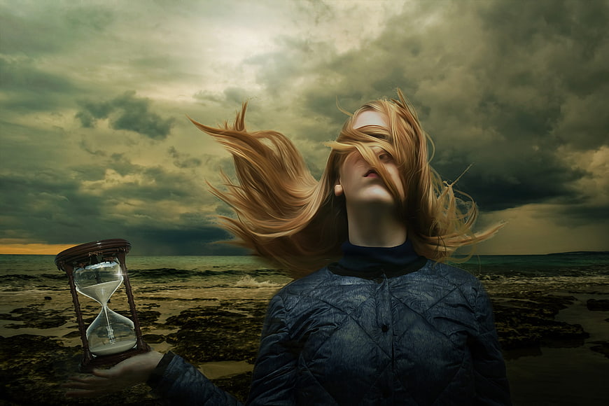 Woman with hourglass on stormy coast