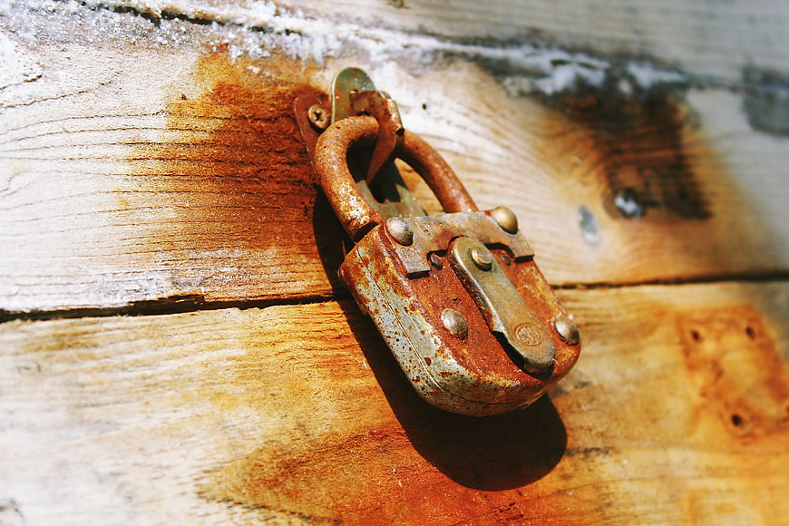 Rusty vintage padlock on weathered wooden surface