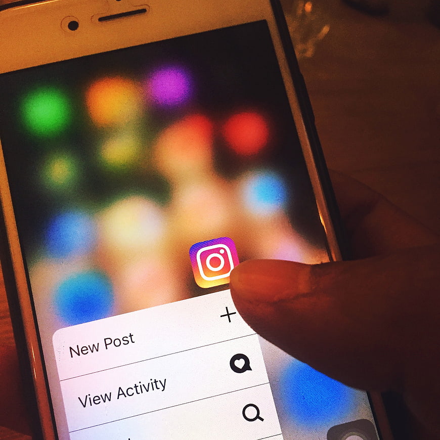 Close-up of finger tapping Instagram app on smartphone screen