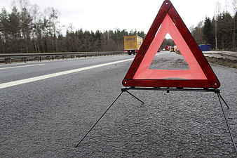 Red Warning Triangle on Highway Shoulder with Traffic