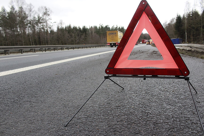Red Warning Triangle on Highway Shoulder with Traffic