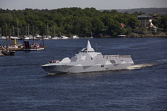 Modern gray naval warship sailing in blue water