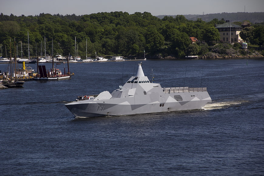 Modern gray naval warship sailing in blue water
