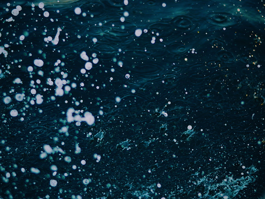Dark blue water surface with bubbles and ripples