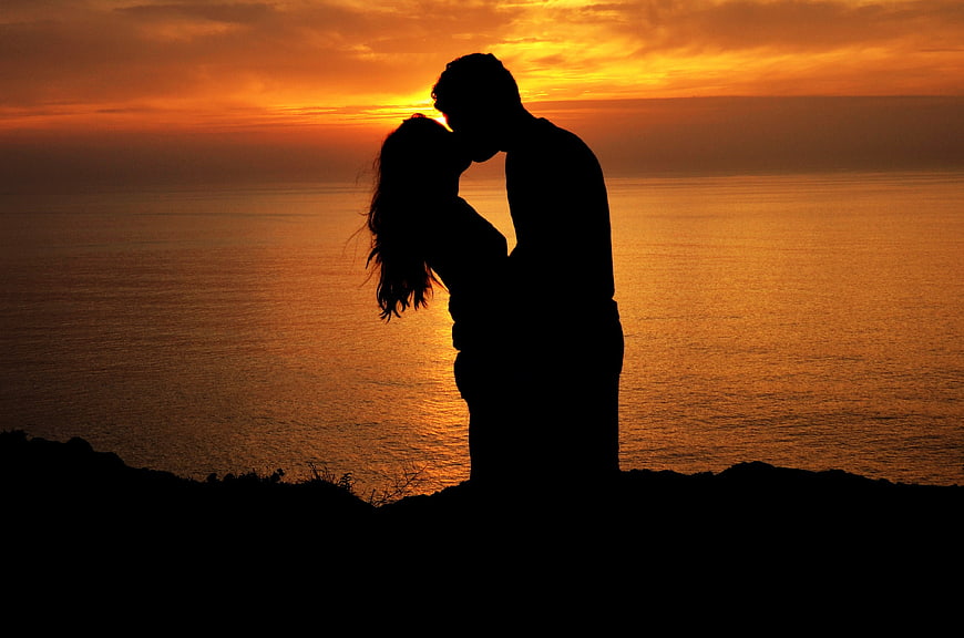 Silhouette of Romantic Couple Kissing at Sunset by the Sea