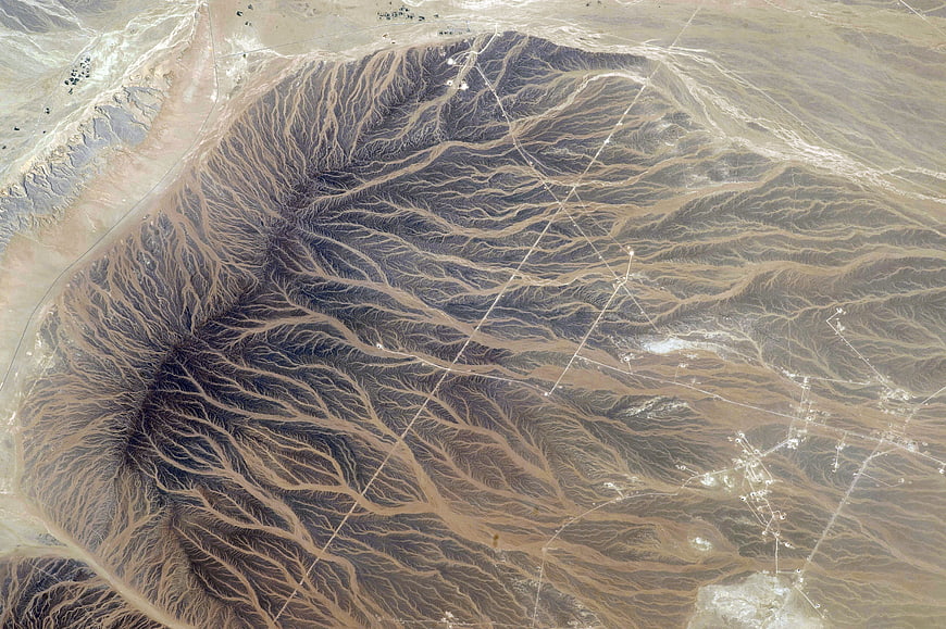 Aerial view of desert landscape with erosion patterns and oil fields