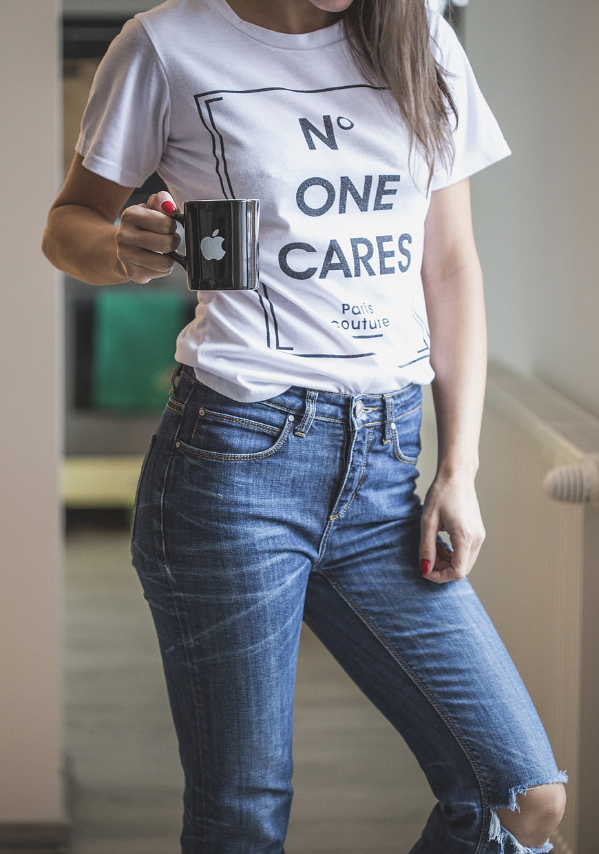 Woman in White Graphic Tee and Ripped Jeans Holding Black Mug