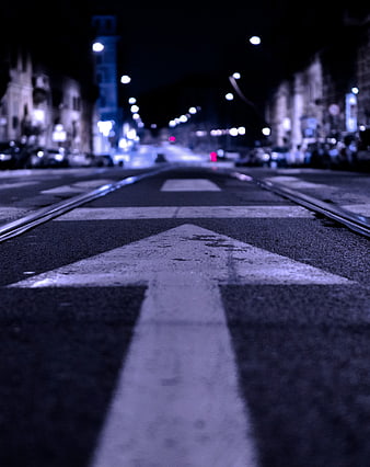 Low angle night shot of white directional arrow on city street