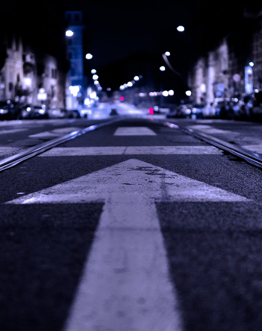 Low angle night shot of white directional arrow on city street