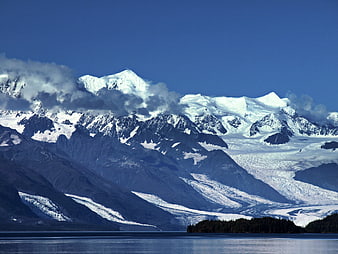Snow-Capped Mountain Peaks and Glacier Over Calm Blue Water