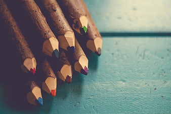 Close-up of wooden colored pencils on teal background