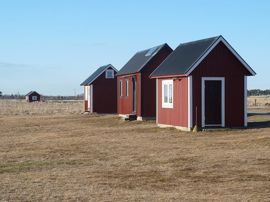 Red wooden cabins in a field with solar panels
