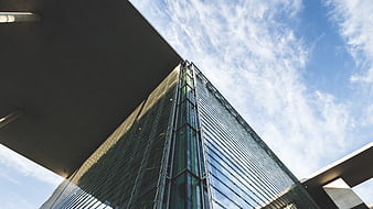 Low angle view of modern glass skyscraper against blue sky
