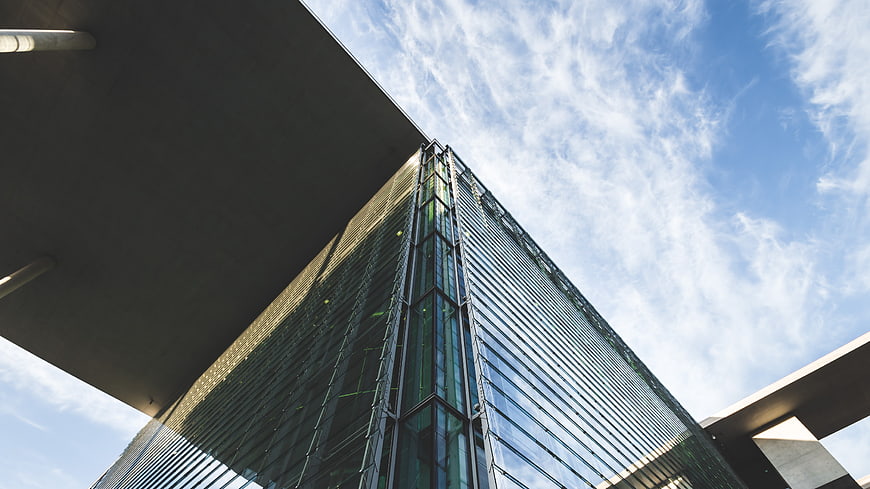 Low angle view of modern glass skyscraper against blue sky