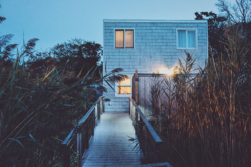 Modern House at Dusk with Wooden Walkway and Reeds
