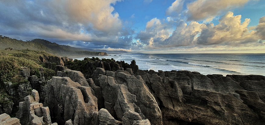 Dramatic Rocky Coastline with Ocean Waves and Cloudy Sky