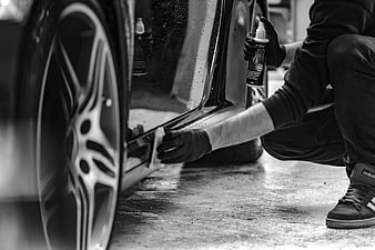 Man Applying Car Polish To Vehicle Side Panel In Black And White
