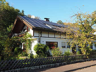 Residential House With Rooftop Solar Panels And Garden Fence