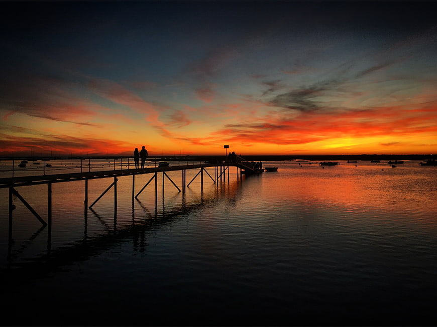 Silhouetted Couple on Pier at Vibrant Sunset