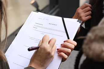 Close-up of hands writing on a clipboard with a survey form