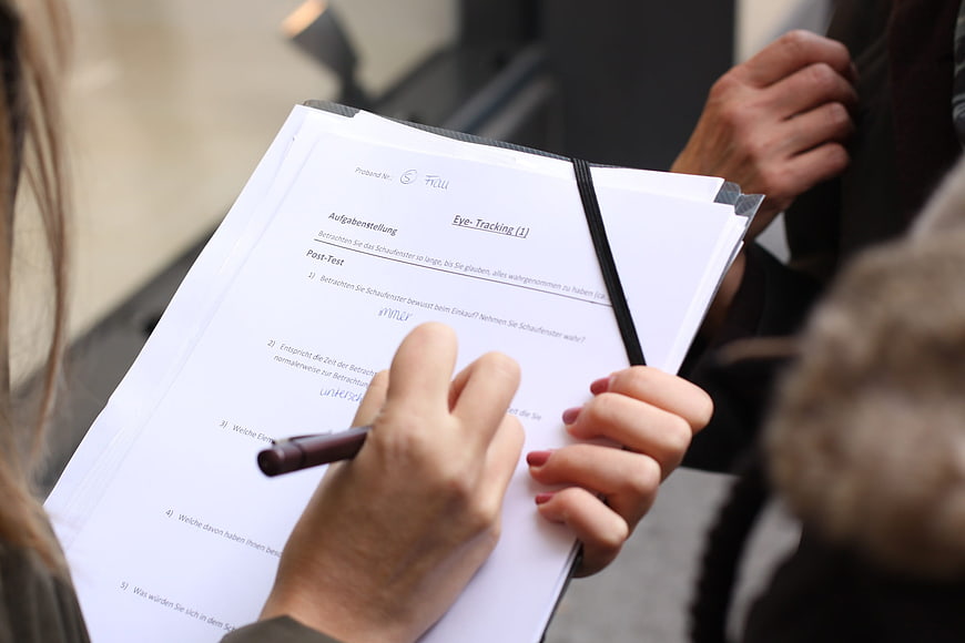 Close-up of hands writing on a clipboard with a survey form