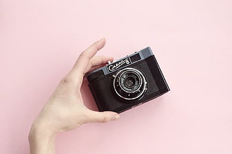Hand Holding Vintage Camera on Pink Background