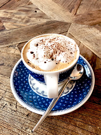 Cappuccino with foam and cocoa on rustic wooden table