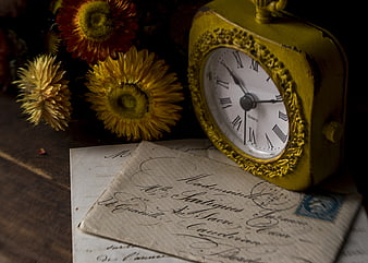 Vintage yellow clock and old handwritten letter with dried flowers