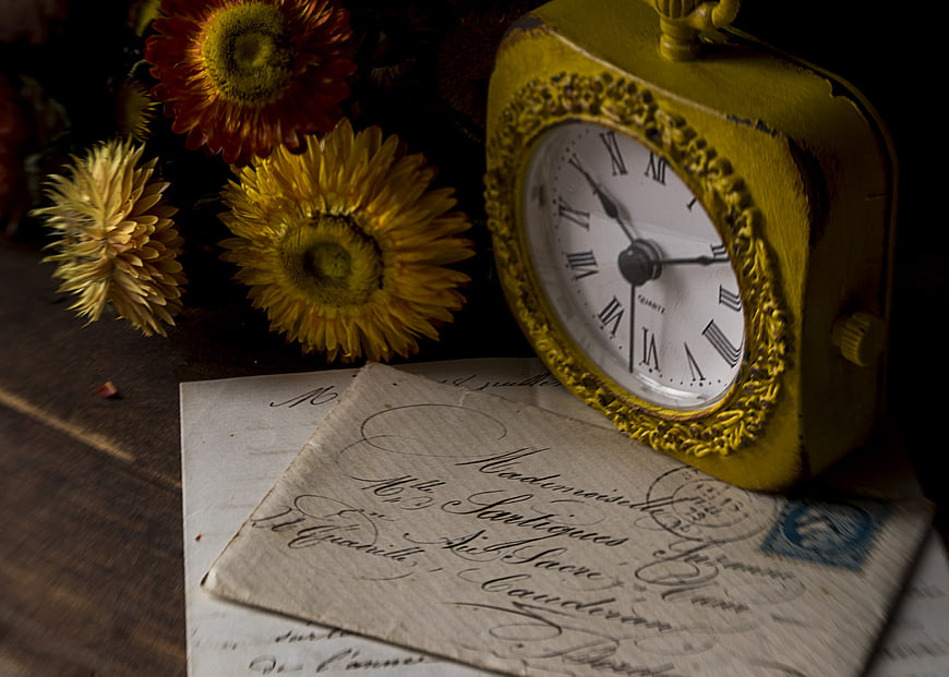 Vintage yellow clock and old handwritten letter with dried flowers