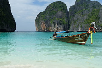 Traditional Thai Longtail Boat Moored In Turquoise Water Near Limestone Cliffs