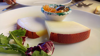 Gourmet cheese slices with honey and salad on white plate