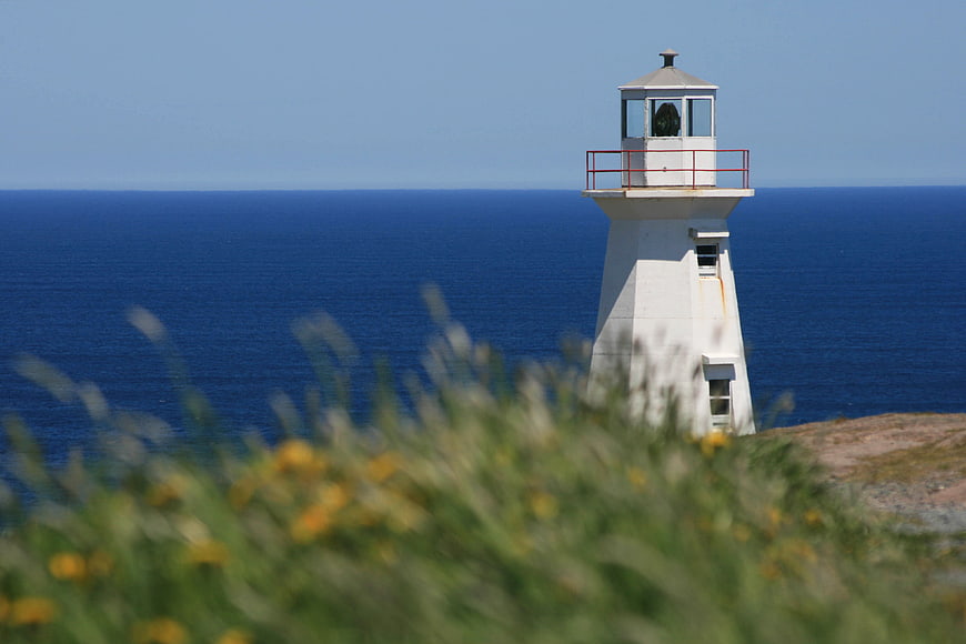 White Lighthouse on Coastal Cliff Overlooking Blue Ocean