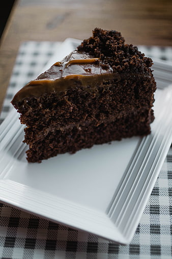 Slice of moist chocolate cake with caramel frosting on white plate
