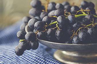 Close-up of ripe dark grapes in a rustic metal bowl